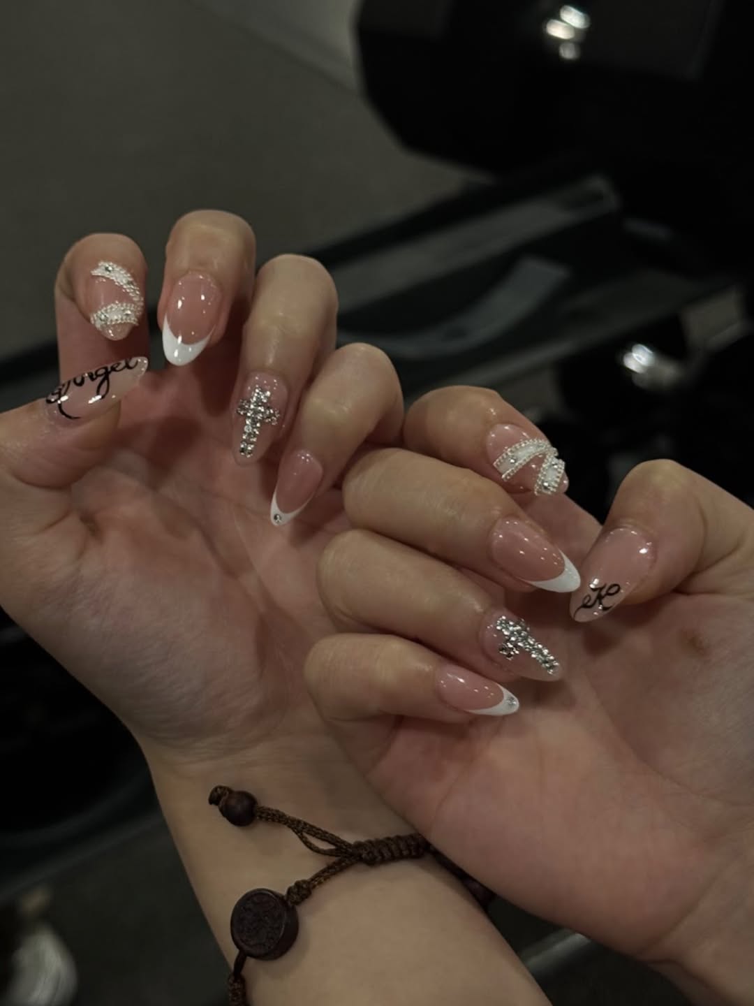 French tip nails with rhinestone cross accents and cursive script nail art