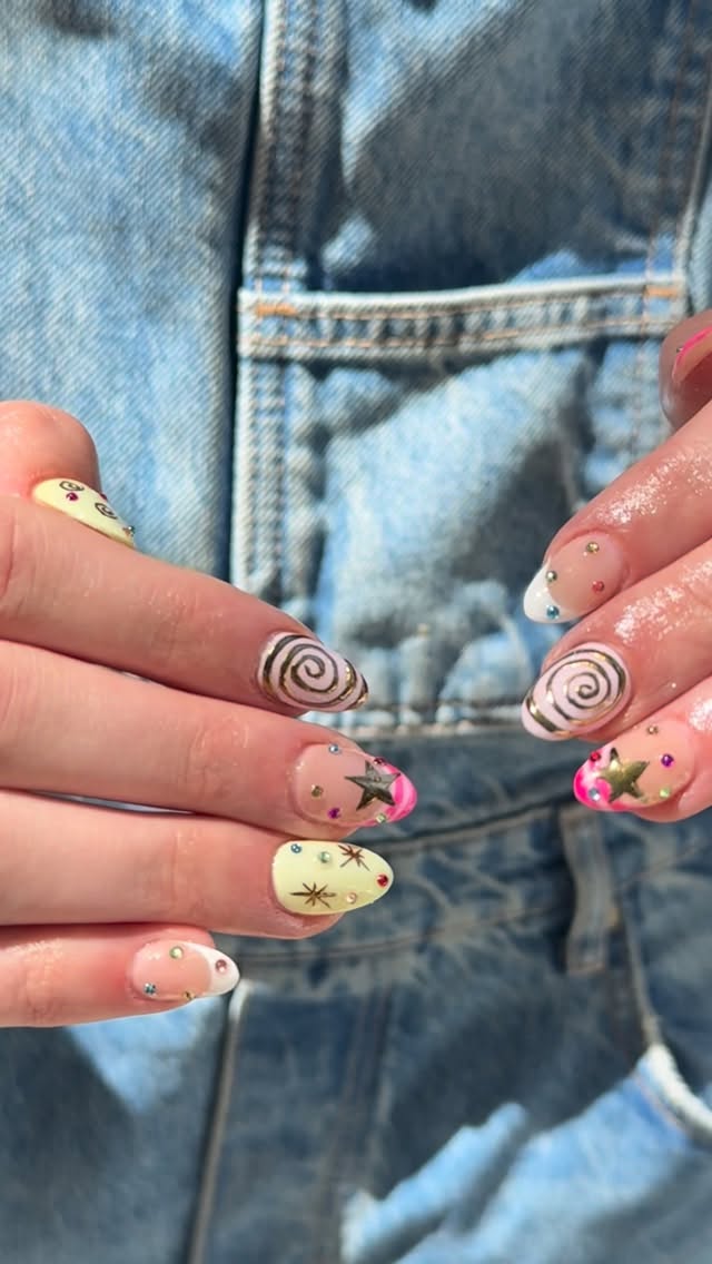 Cream nails with hand-painted gold spirals, stars, and rhinestones