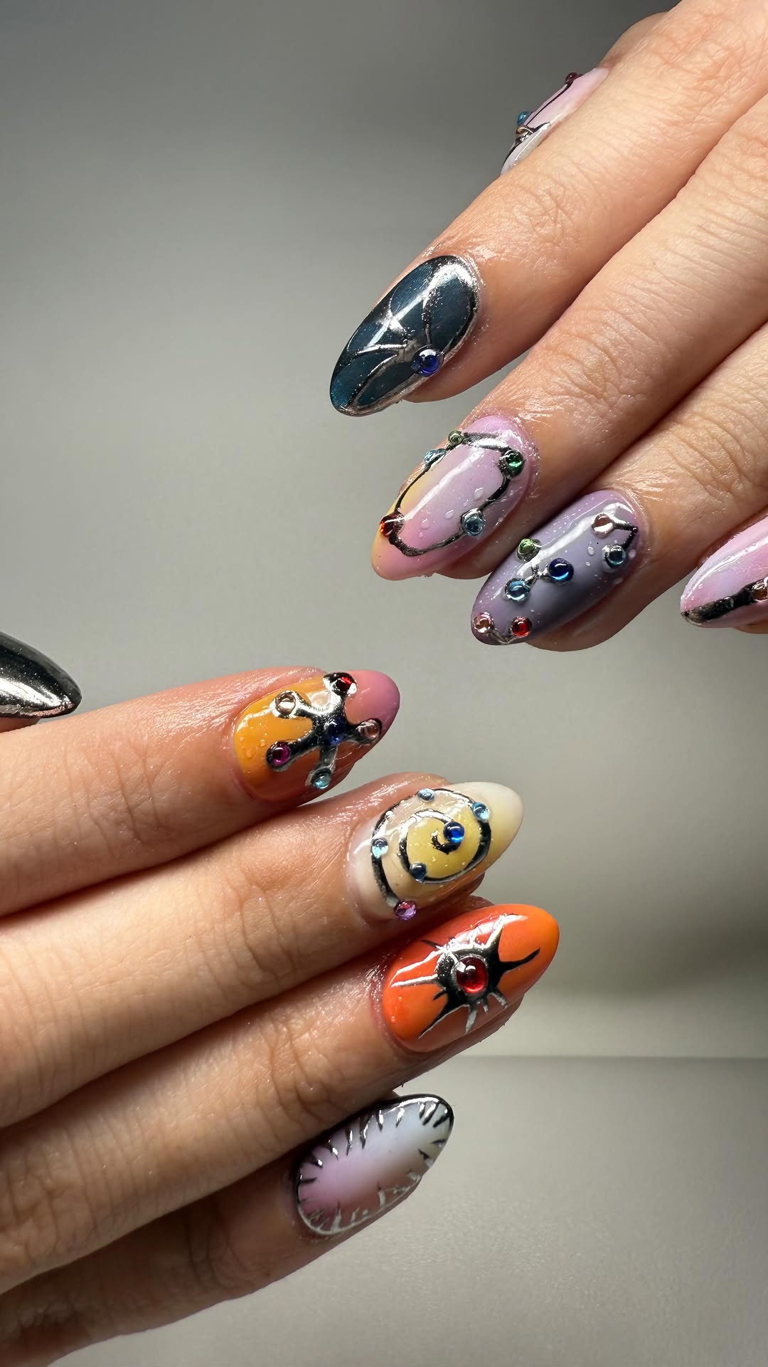 Colorful abstract cosmic-inspired nail art with rhinestone accents